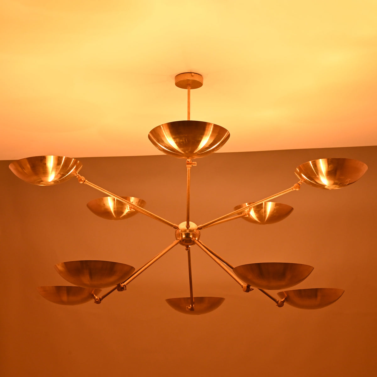 Night view of brass bowl chandelier illuminated with warm indirect lighting across all ten bowl shades.
