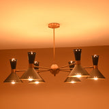 Side angle of illuminated 12-light brass and black cone chandelier with brushed brass arms and warm diffused lighting.