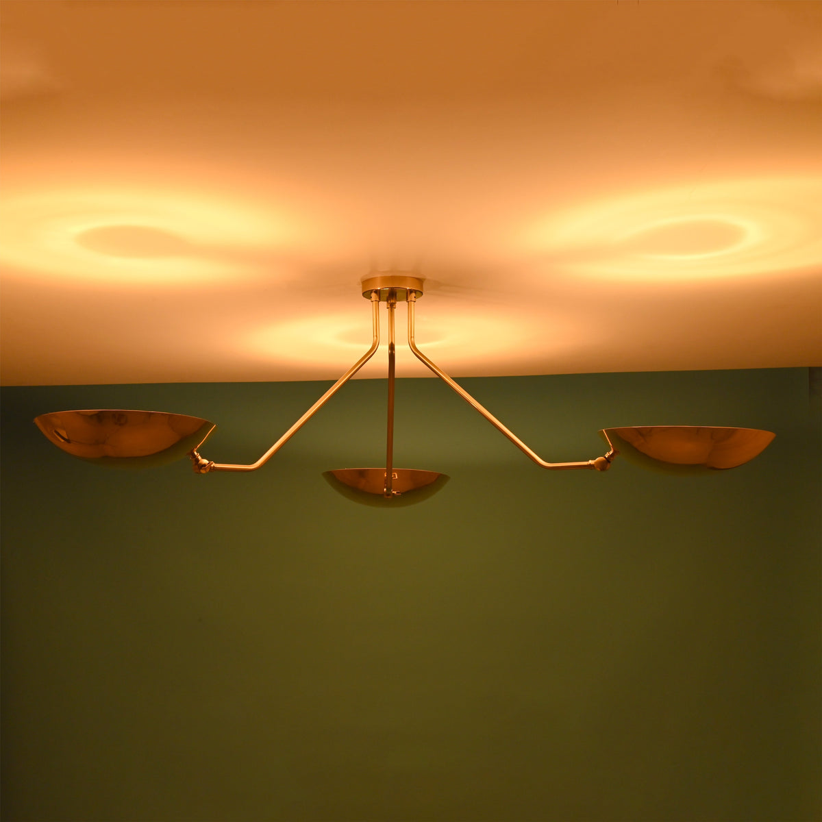 3 light brass bowl ceiling light emitting warm indirect ambient glow against modern interior wall