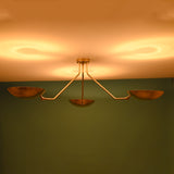 3 light brass bowl ceiling light emitting warm indirect ambient glow against modern interior wall