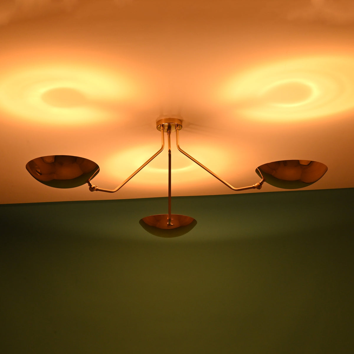 3 light brass bowl flushmount ceiling light illuminated in dark room showing indirect halo lighting effect