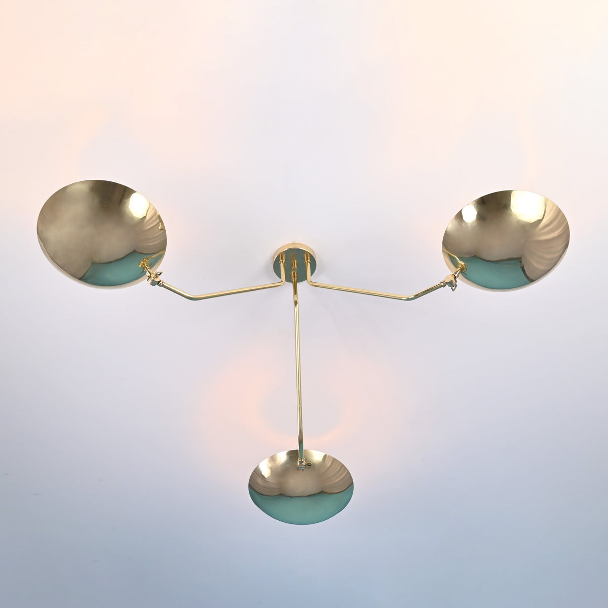 Bottom view of 3 light brass disc ceiling light with bowl shaped shades and clean symmetrical arms