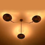 Brass disc style 3 light chandelier creating soft indirect uplighting and warm ambient illumination