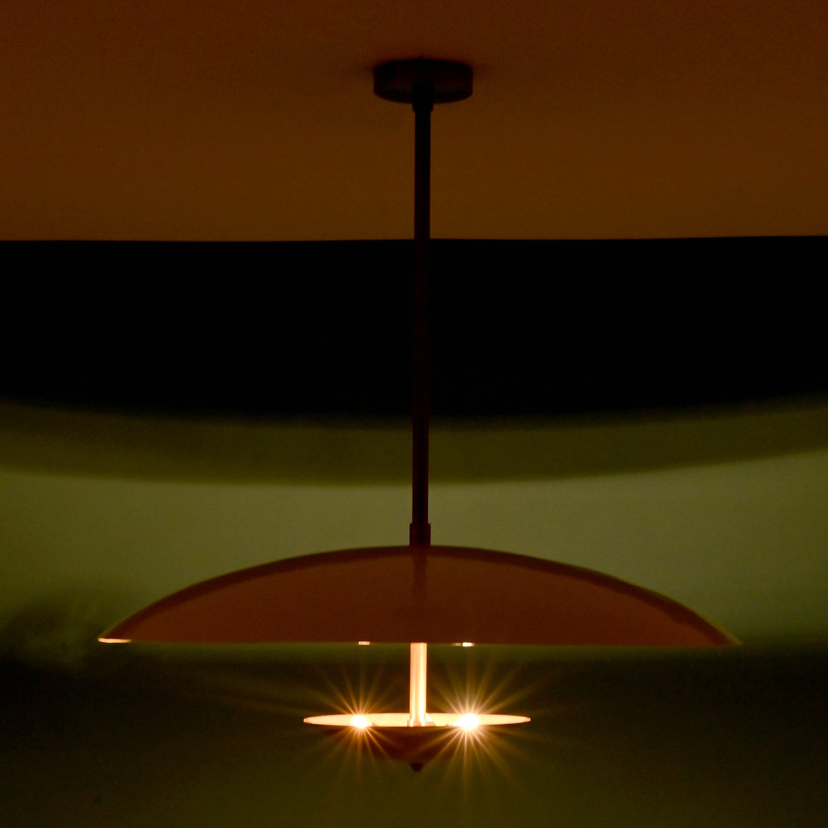Night view of 3 light disc style brass chandelier creating warm indirect lighting ambiance