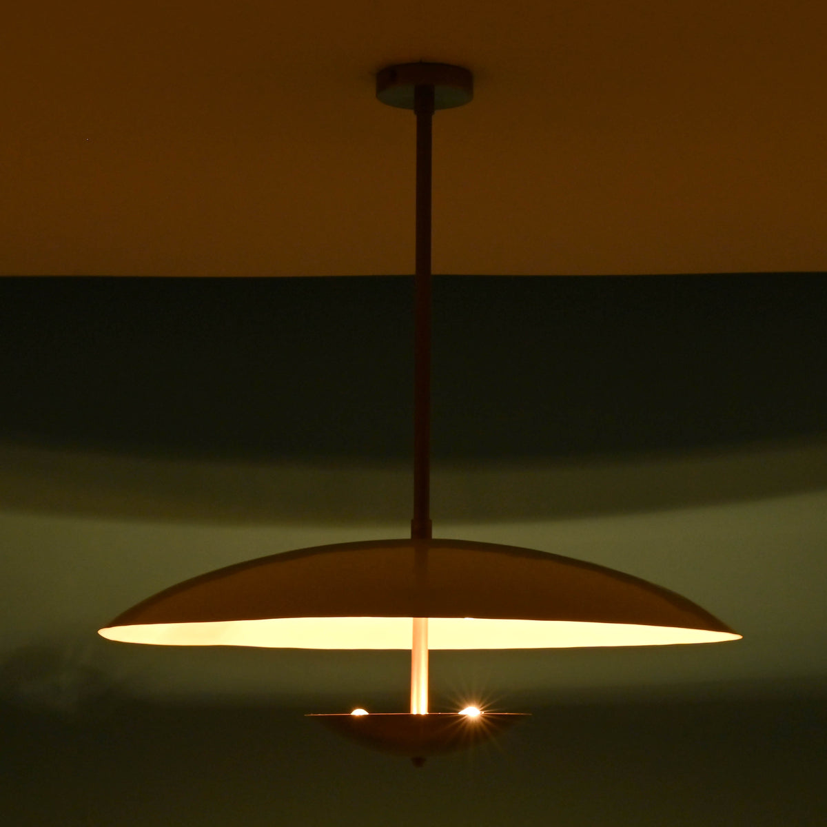 Wide night view of 3 light disc style brass chandelier with indirect lighting and modern elegance