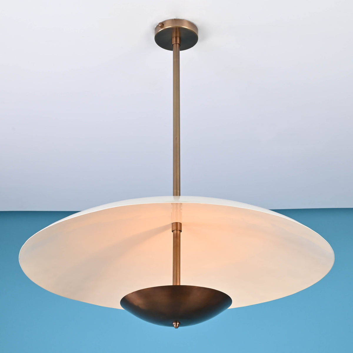 3 light disc style brass chandelier illuminated with warm ambient indirect lighting