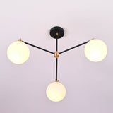 Angled perspective of a modern brass chandelier featuring three glowing opal glass globes.
