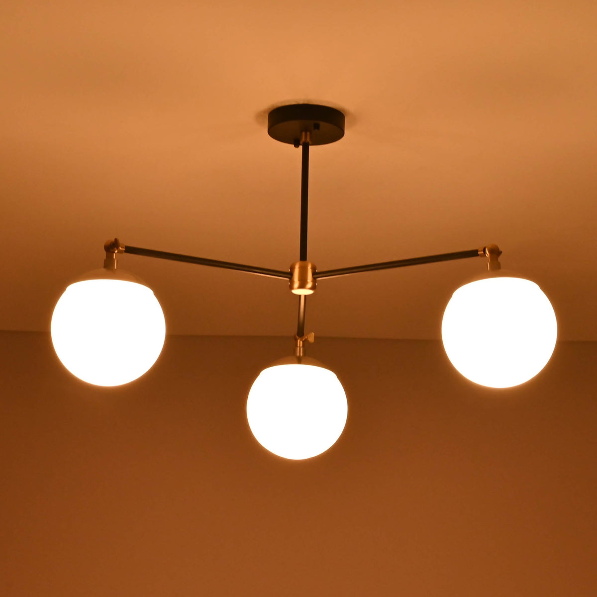 Bottom view of a 3 light opal glass globe chandelier highlighting balanced arms and glowing spheres.