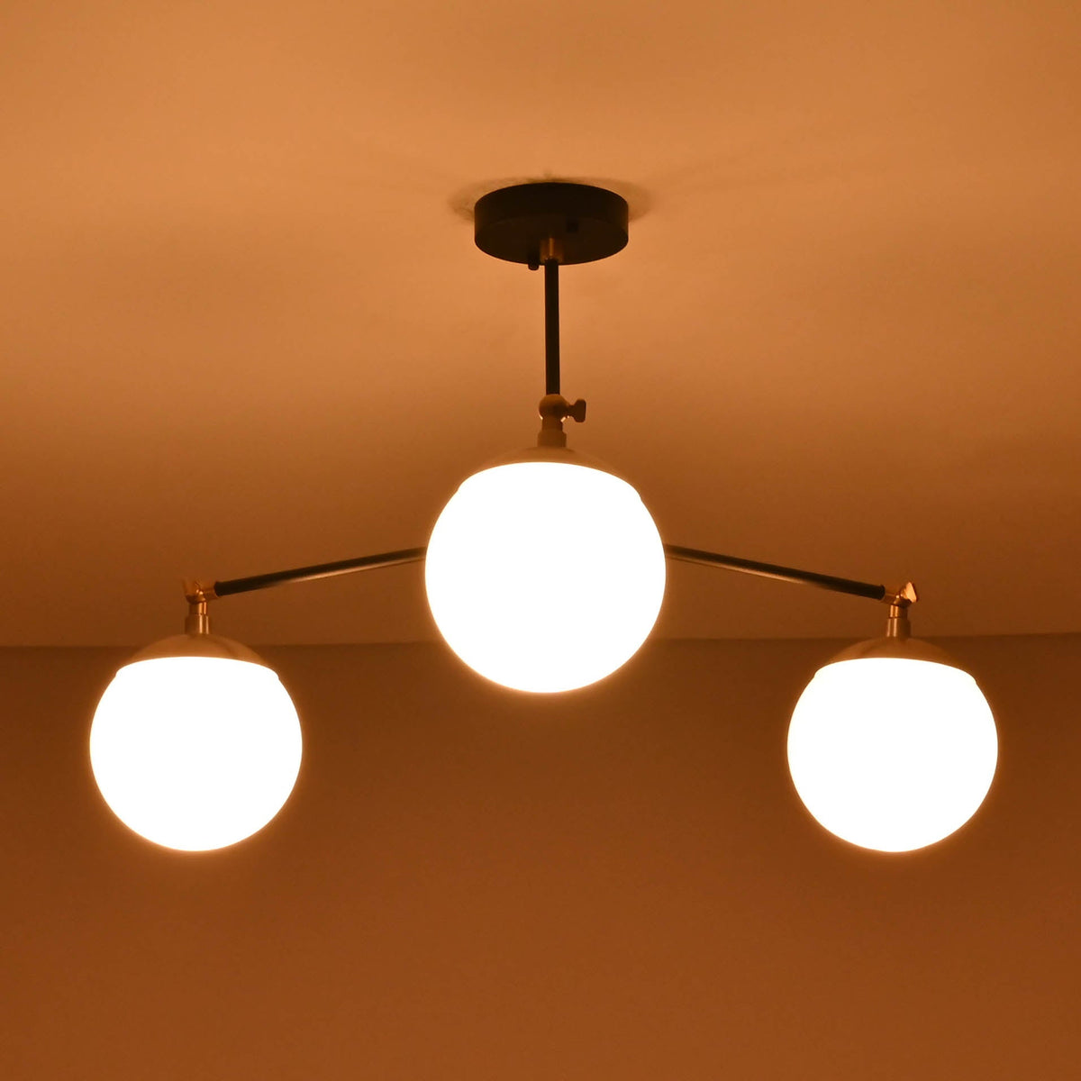 Opal glass globe brass chandelier creating a warm, ambient ceiling glow in a modern space.