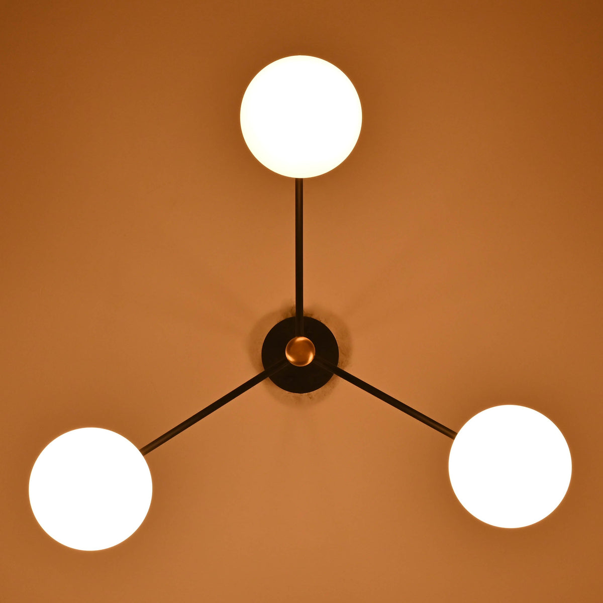Three light opal glass globe chandelier illuminated with warm ambient lighting in a cozy interior.