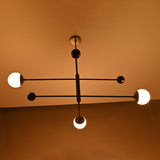 Matte black balance chandelier softly glowing in warm ambient light – diagonal angle