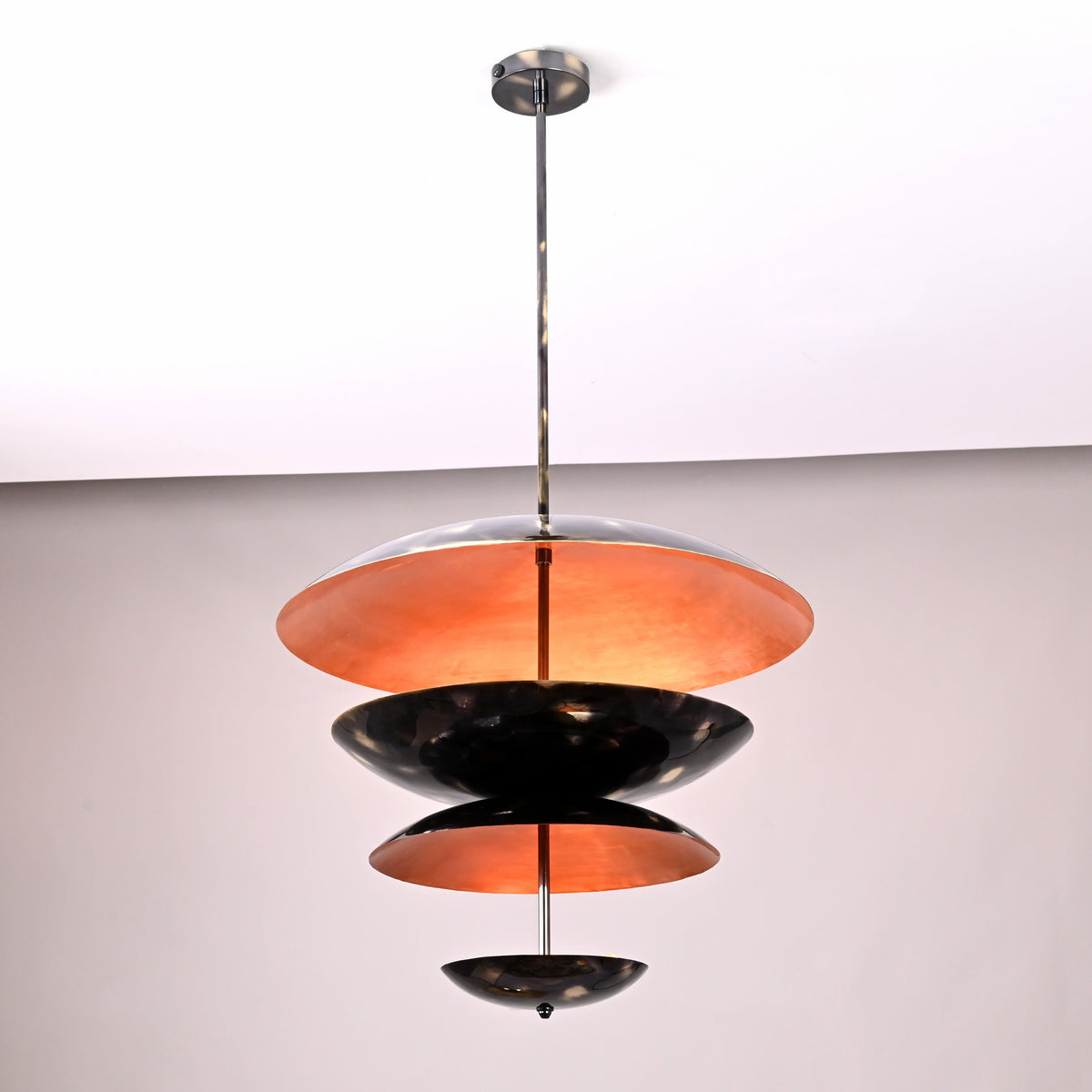 Three-tier bowl shade chandelier in blackened brass with warm uplighting