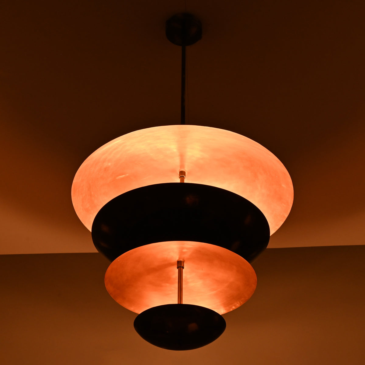 Side view of modern tiered brass chandelier with warm ambient lighting