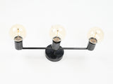 Modern brass vanity wall light with three exposed bulbs