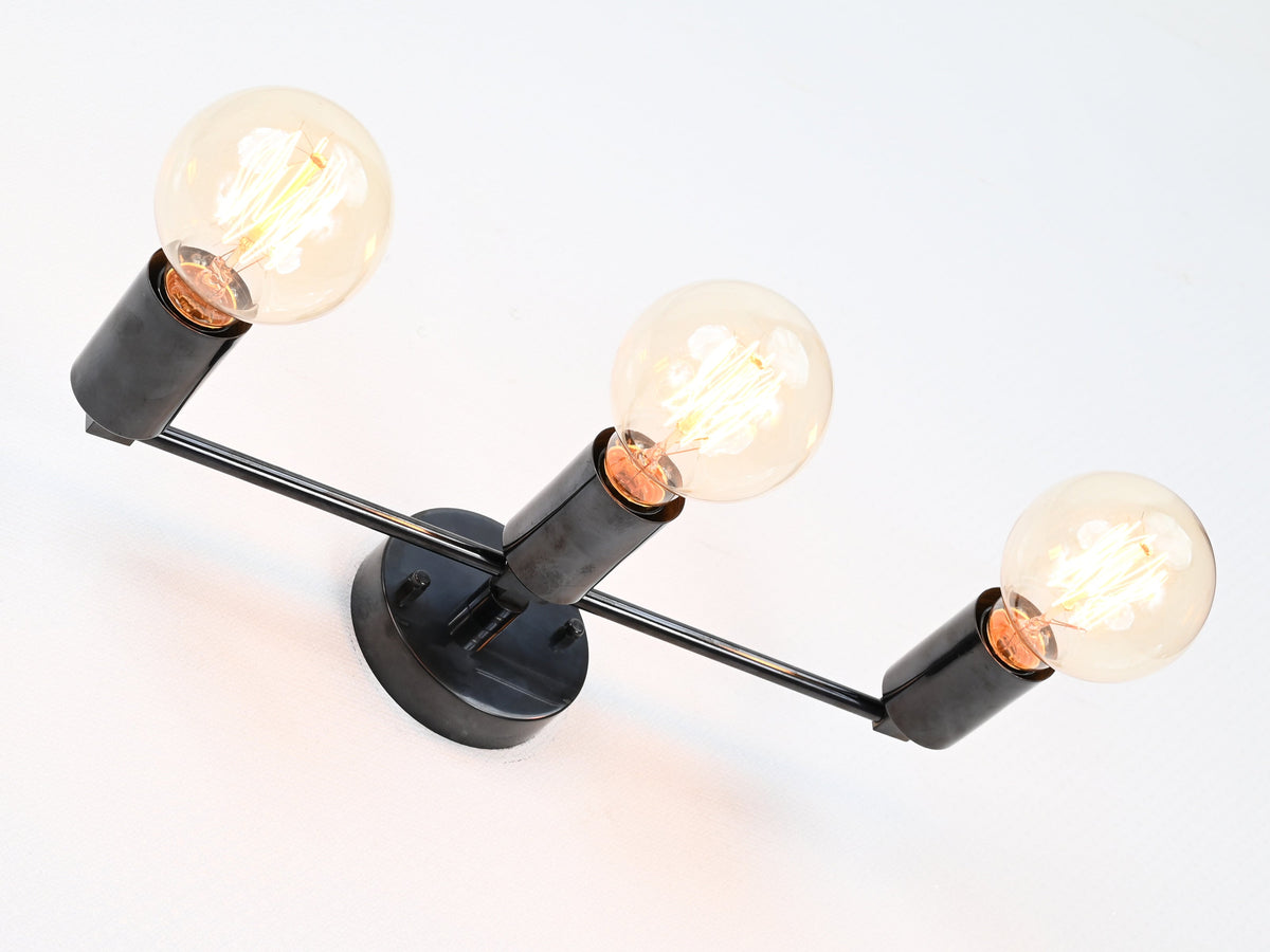 Linear three-light brass wall sconce with exposed bulbs