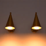 Two matching cone-shaped wall sconces in a warm brass or bronze finish, mounted side by side on a wall and casting a soft warm glow downward.