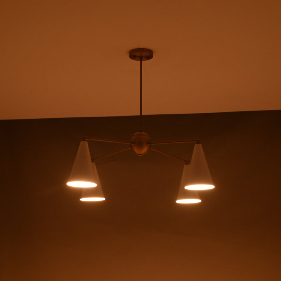 Brass chandelier featuring four white cone shades and a central brass sphere, modern mid-century design.