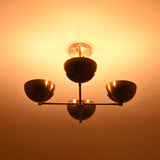 4 bowl brass chandelier casting a warm upward glow, highlighting its indirect lighting design and elegant brass ceiling canopy.