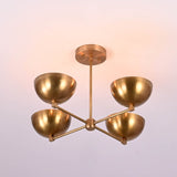 4 bowl brass chandelier illuminated to show warm ambient indirect lighting that softly reflects off the brushed brass finish.