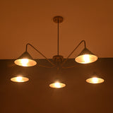 Warm-lit view of 5-light brass chandelier showing glowing cone shades creating soft ambient lighting.