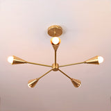 Overhead top view of 5-light brass ceiling fixture displaying perfect symmetry and modern geometric form in brushed brass with soft ambient glow.