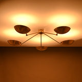 Soft warm illumination from a handcrafted 5-light brass flushmount light with wide reflective brass shades.
