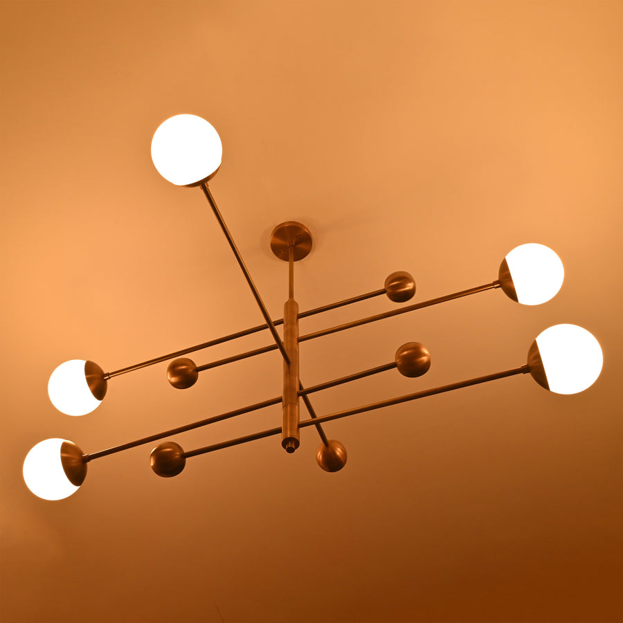 Modern 5-light brass chandelier with opal glass globes arranged on linear brass arms for balanced contemporary lighting.