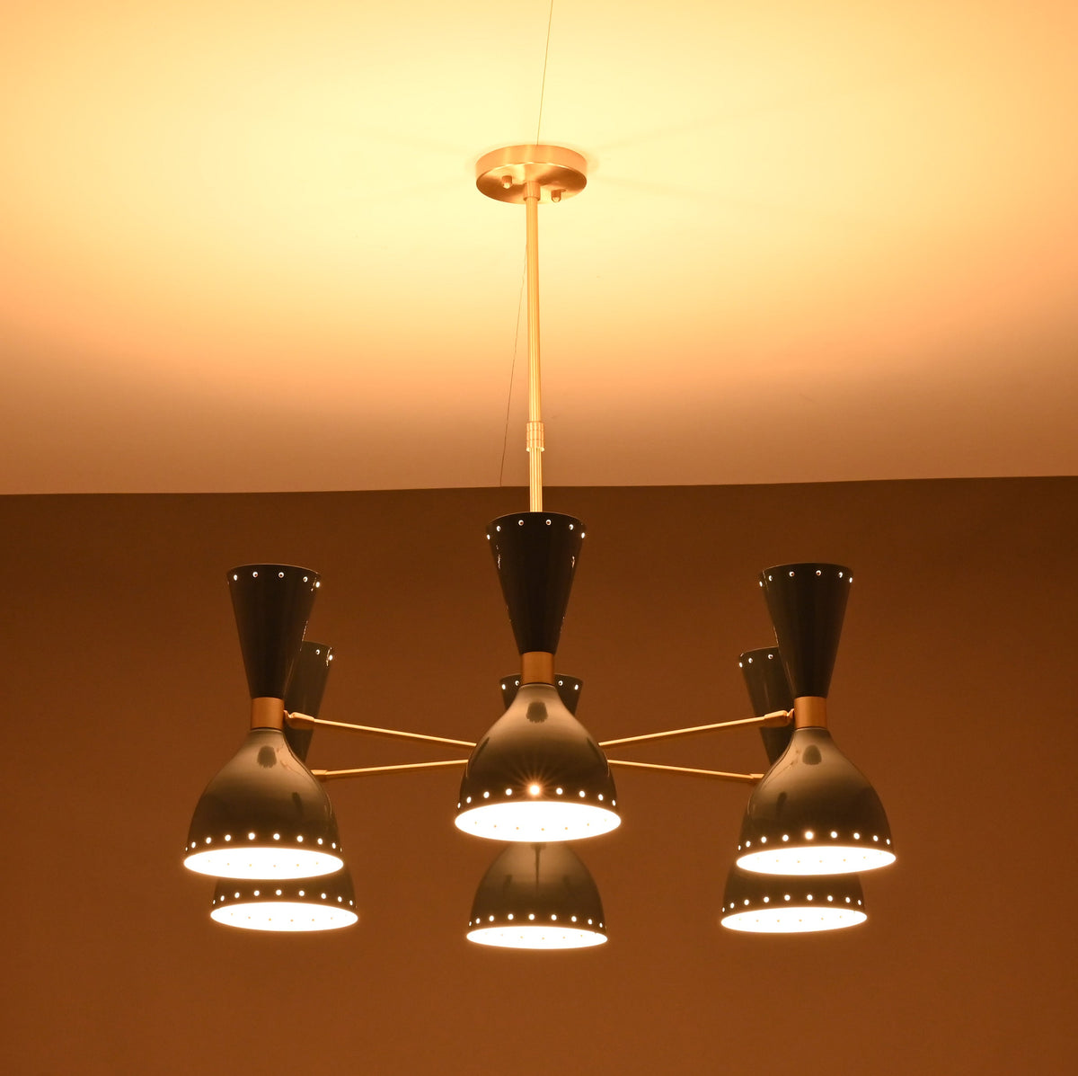 Side profile of illuminated 6 Brass Diabolo chandelier showcasing sculptural diabolo shades and brass detailing