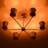 6 light brass chandelier emitting warm ambient lighting through perforated cone shades, ideal for dining and living spaces.