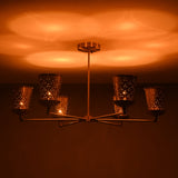 Side view of 6 light brass cone shade chandelier illuminated with warm ambient glow, creating soft indirect uplighting.