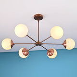 Angled view of handcrafted 6 light glass globe brass chandelier with brushed brass finish and opal glass globes