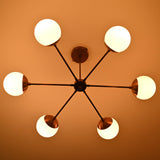 Illuminated 6 light glass globe brass chandelier highlighting brushed brass arms and soft diffused light