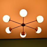 Warm lit 6 light glass globe brass chandelier showcasing symmetrical mid-century design and handcrafted brass details