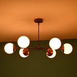Angled night view of 6 light glass globe brass chandelier with glowing opal glass globes and elegant brass finish