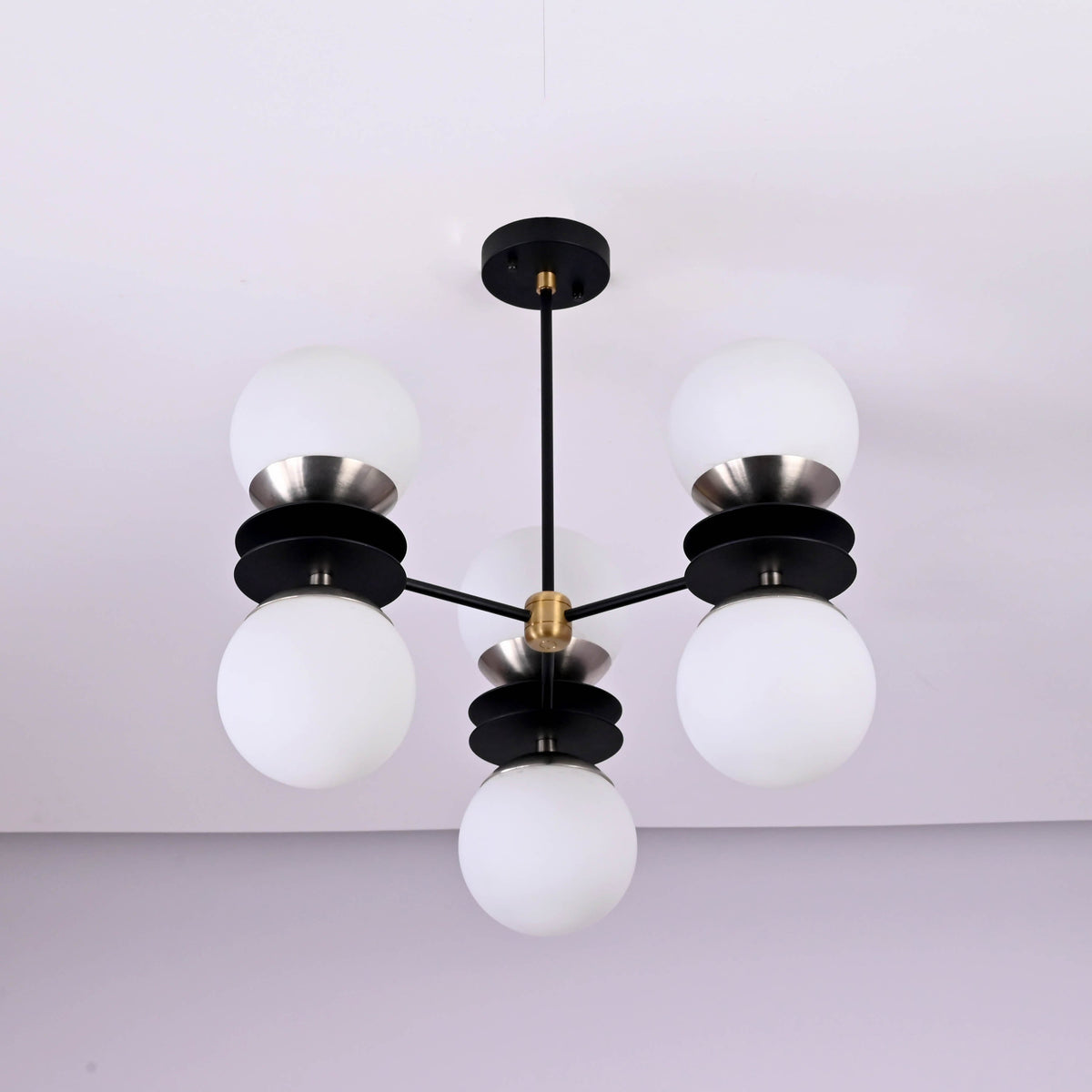 Bottom view of six light brass chandelier featuring opal glass globes and layered disc design