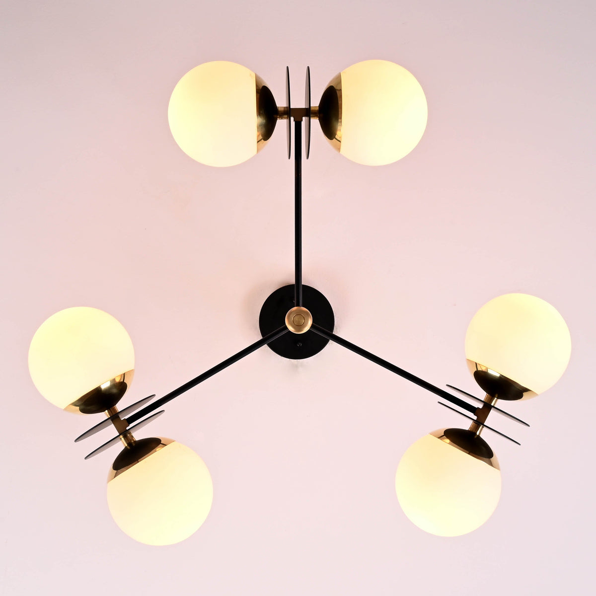Bottom view of a 6-light opal glass globe brass chandelier highlighting balanced arms and sculptural brass center.