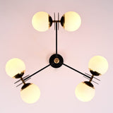 Bottom view of a 6-light opal glass globe brass chandelier highlighting balanced arms and sculptural brass center.