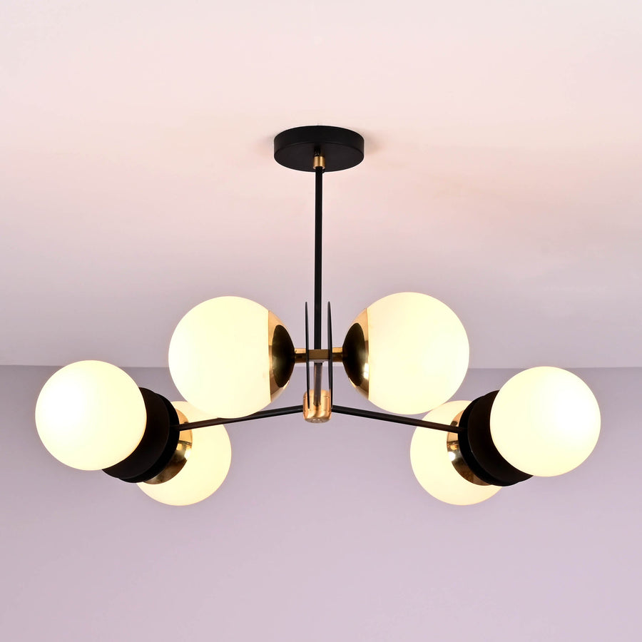 Front view of a 6 opal glass globe brass chandelier with black arms and brushed brass details, providing warm ambient ceiling lighting.