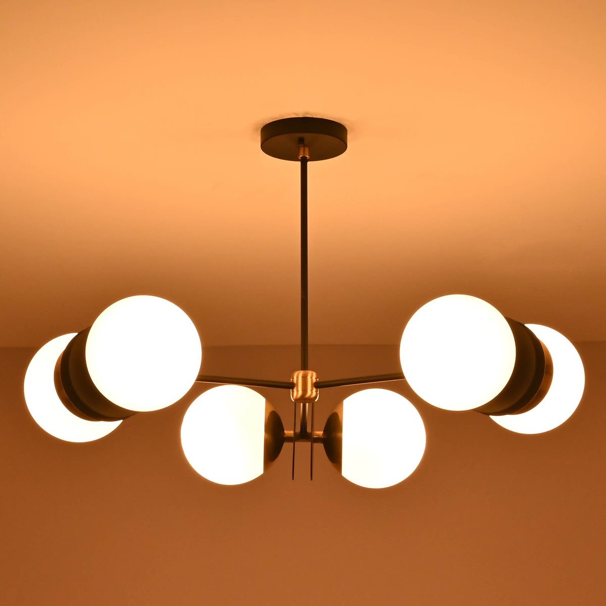 Modern industrial brass chandelier with six opal glass globes enhancing ambient lighting in an elegant interior.