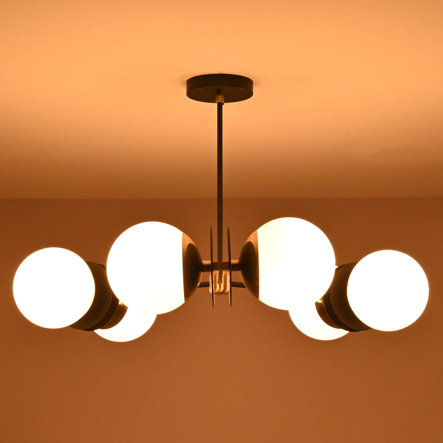 Front view of a 6 opal glass globe brass chandelier with black arms and brushed brass details, providing warm ambient ceiling lighting.