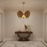 A modern five-light brass chandelier with a central light bulb glowing warmly, suspended by a single rod from a circular ceiling canopy against a solid white background.