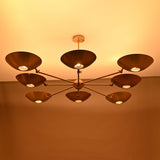 Side view of modern brass disc chandelier casting warm ambient lighting across the ceiling.