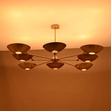 Evening-lit brass disc chandelier with eight disc shades emitting soft warm light in a symmetrical layout.