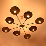 Warm-lit brass disc chandelier with eight glowing bulbs and circular concave brass shades.
