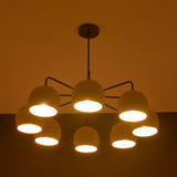 8-light brass chandelier glowing with warm ambient lighting, featuring dome-shaped shades and minimalist arms.