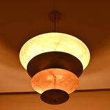 Elegant raw brass hanging light with tiered bowls creating soft ambient lighting