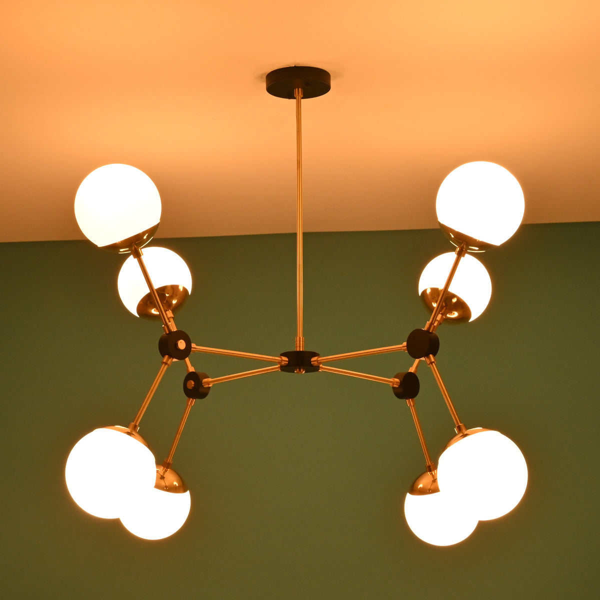 Close-up detail of brass arms, black connectors, and opal glass globe shade on an 8-light modern chandelier.