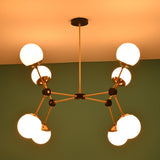 Close-up detail of brass arms, black connectors, and opal glass globe shade on an 8-light modern chandelier.