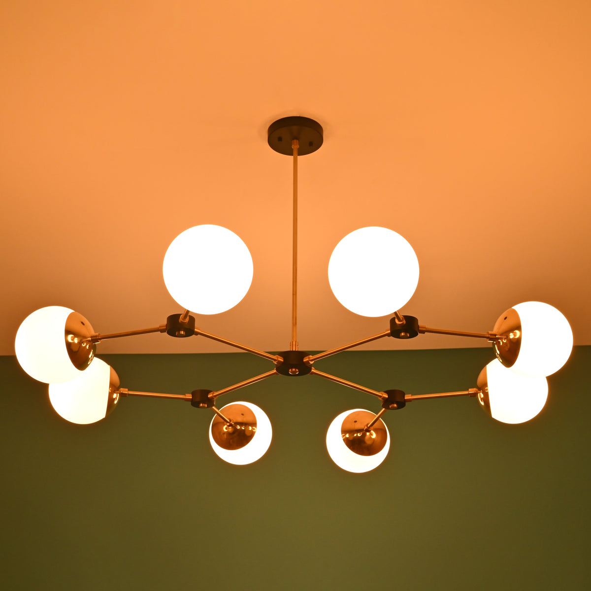 8-light brass linear chandelier glowing warmly in a darkened room, emphasizing opal globe shades and contemporary design.
