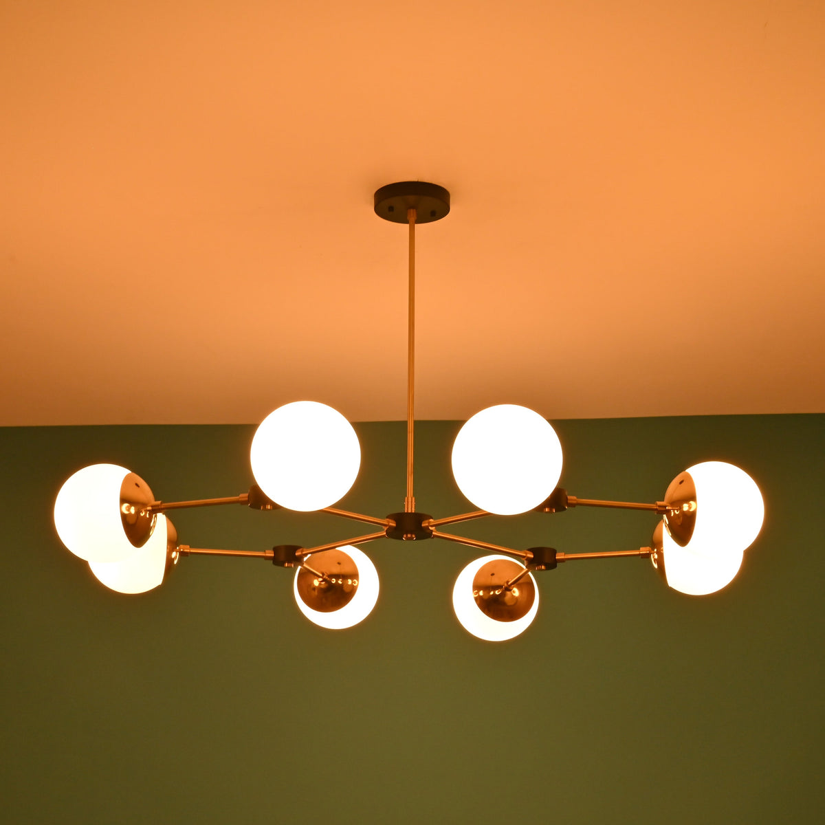 Symmetrical view of an 8-light brass sputnik chandelier with opal glass globes and black accents mounted on a modern ceiling.